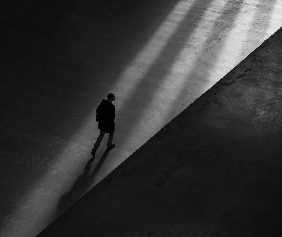 Svert vit bild, en människa som vandrar i mörkret mot ljuset.