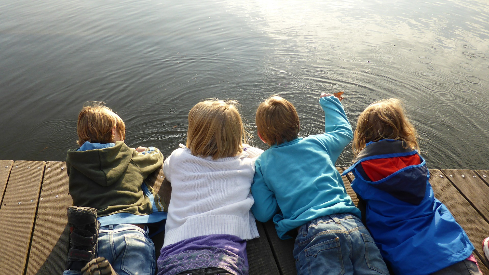 4 barn ligger på bryggan vid vattnet