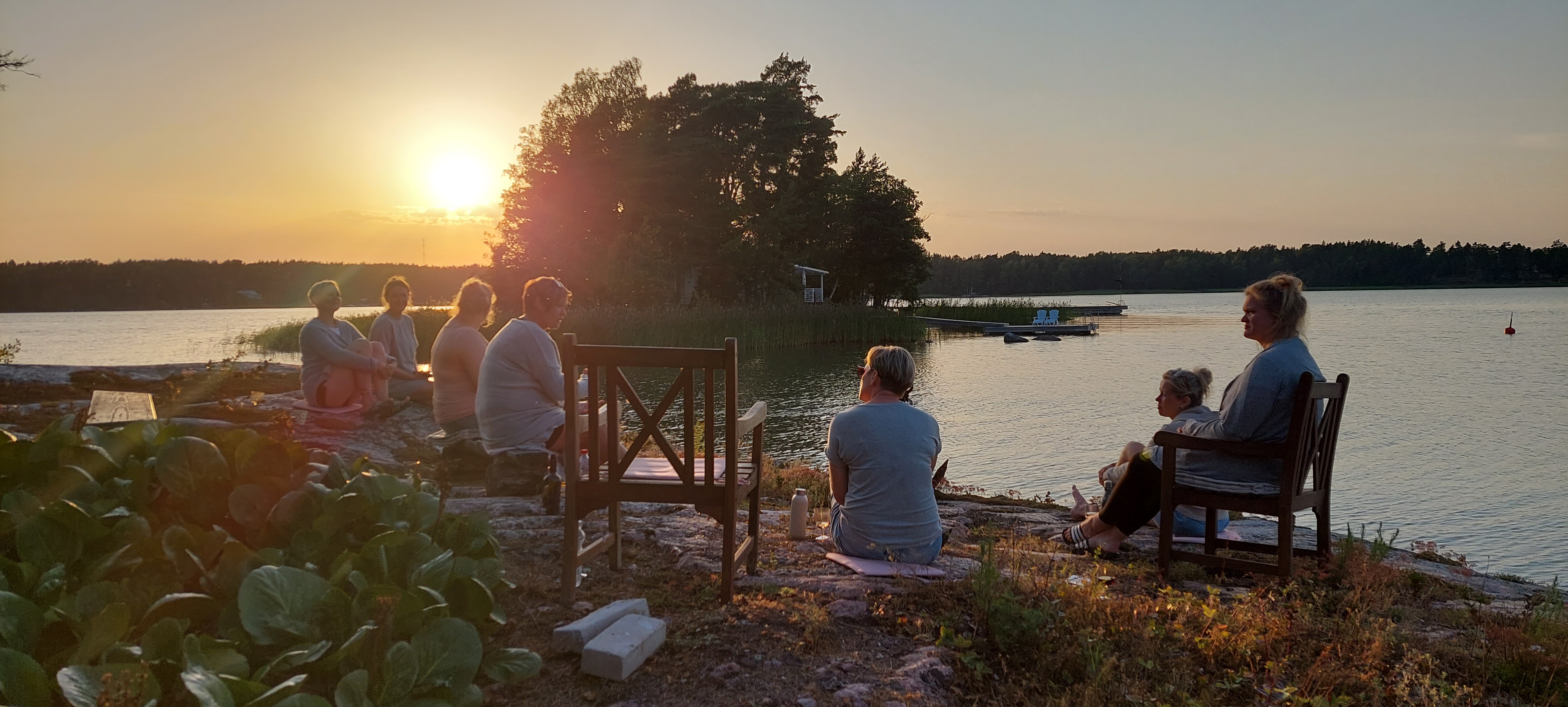sittande kvinnor på ett berg vid havet  i solnedgången
