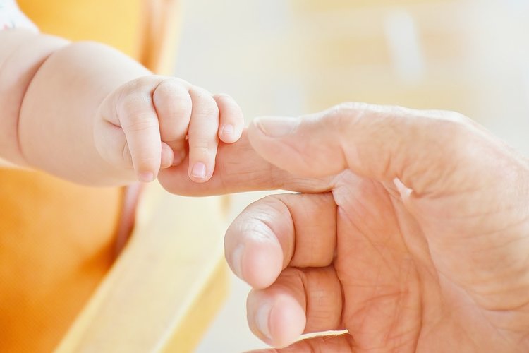 En mans fingrar som rör en babys fingrar