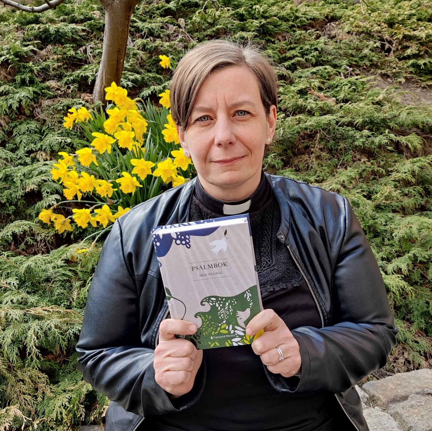 Kyrkoherde Mia Bäck med en psalmbok i handen