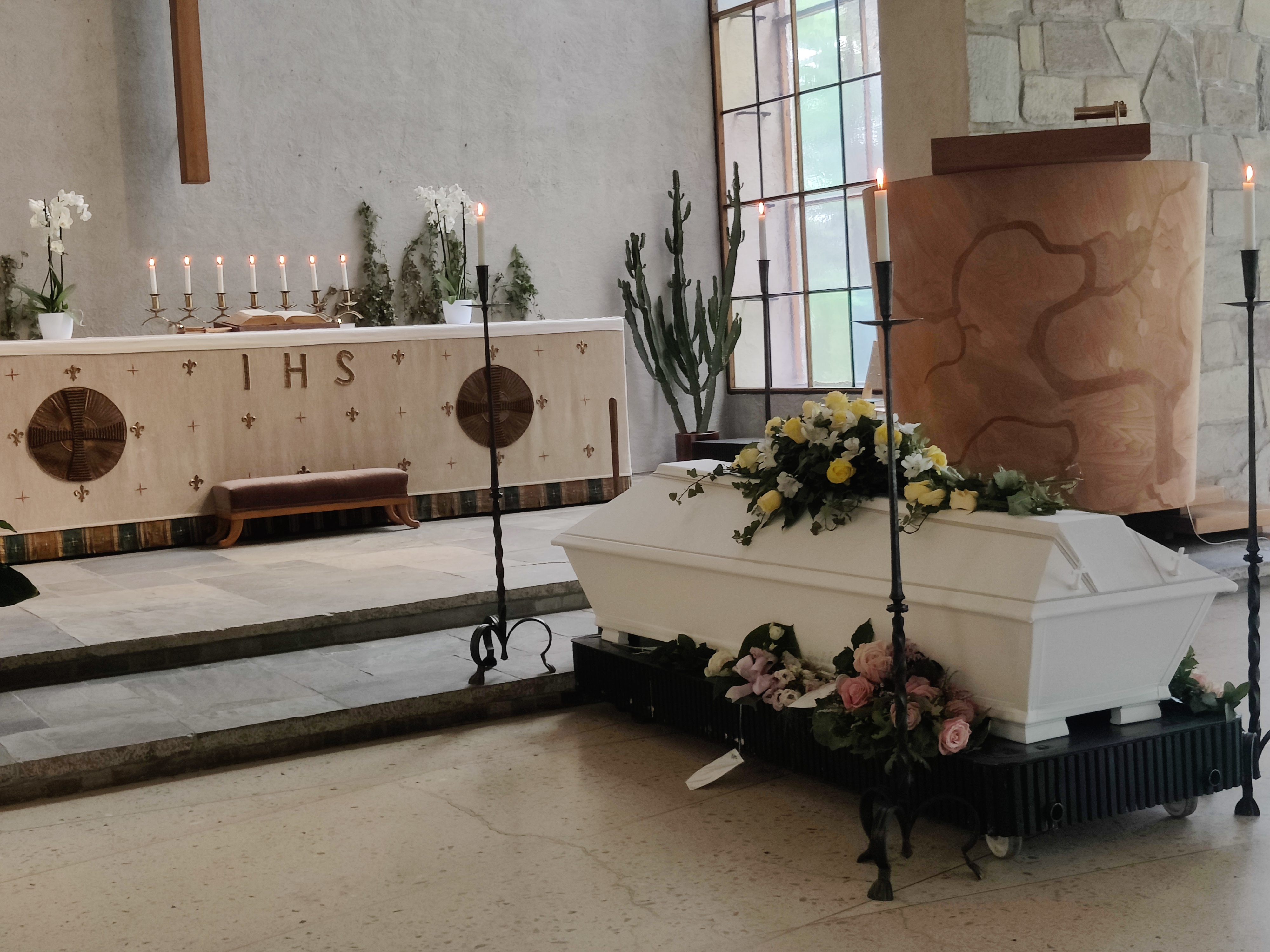 På bilden finns altaret i Uppståndelsekapellet. Framför altaret finns en vit kista med vackra blommor på.